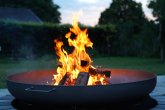 Iron fire pit and burning fire in a garden .