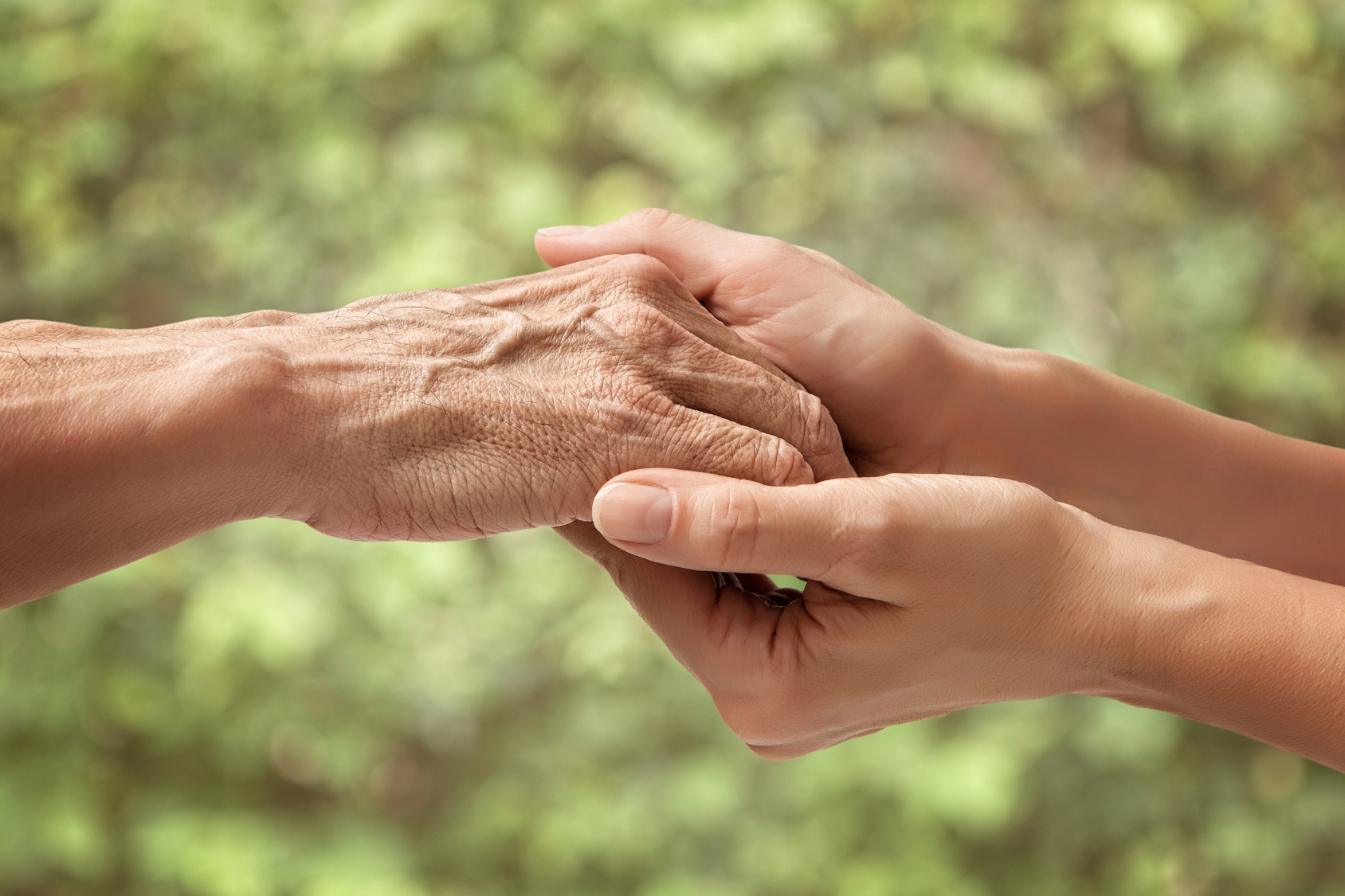 Hands of an elderly senior holding the hand of a woman