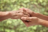 Hands of an elderly senior holding the hand of a woman