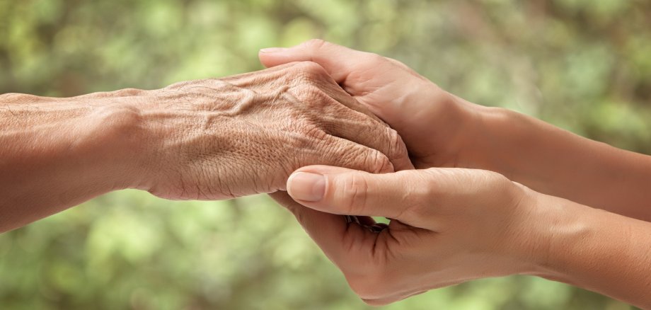 Hands of an elderly senior holding the hand of a woman