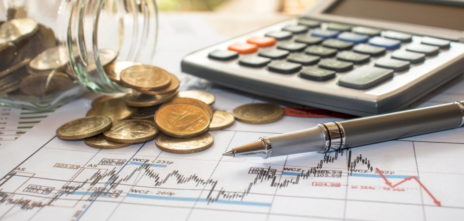 Pens and coins placed on financial reports or stock market chart analysis, placed on the table, financial income tax calculation concepts and financial monitoring concepts.