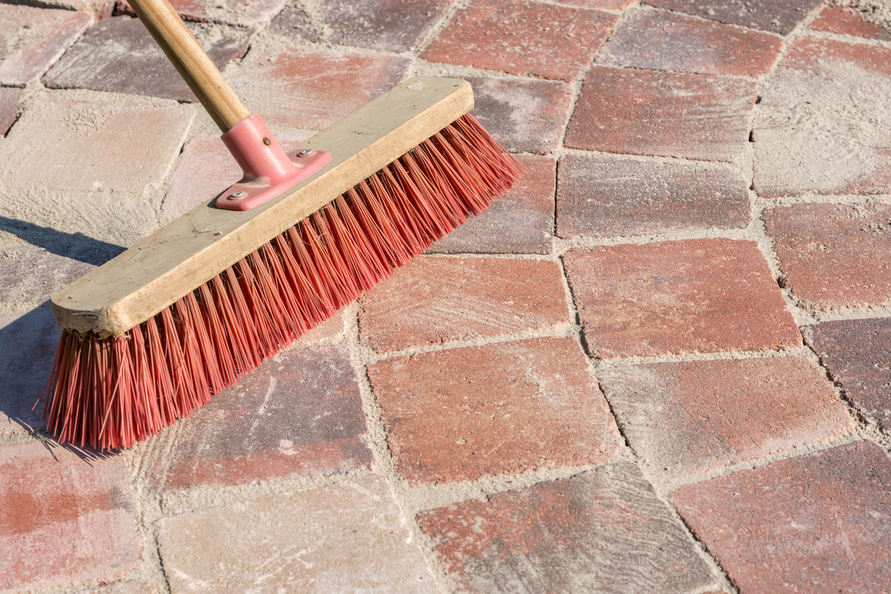 Paved walkway is grouted with fine-grained sand and a broom