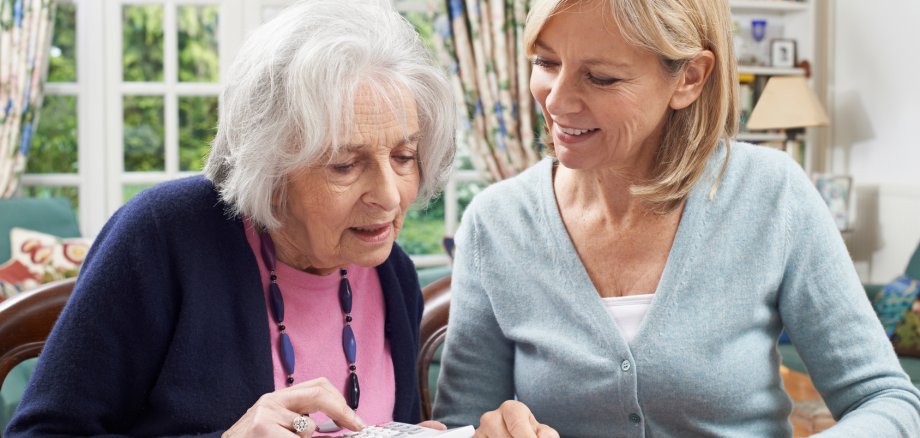 Female Neighbor Helping Senior Woman With Domestic Finances Female Neighbor Helping Senior Woman With Domestic Finances