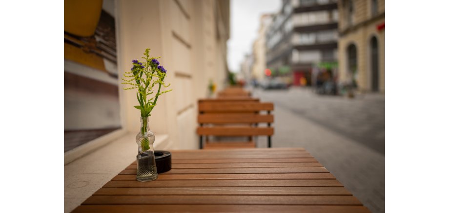 Single glass vase of purple statice and goldenrod flowers on wooden Vienna cafe table Single glass vase of purple statice and goldenrod flowers on wooden Vienna cafe table
