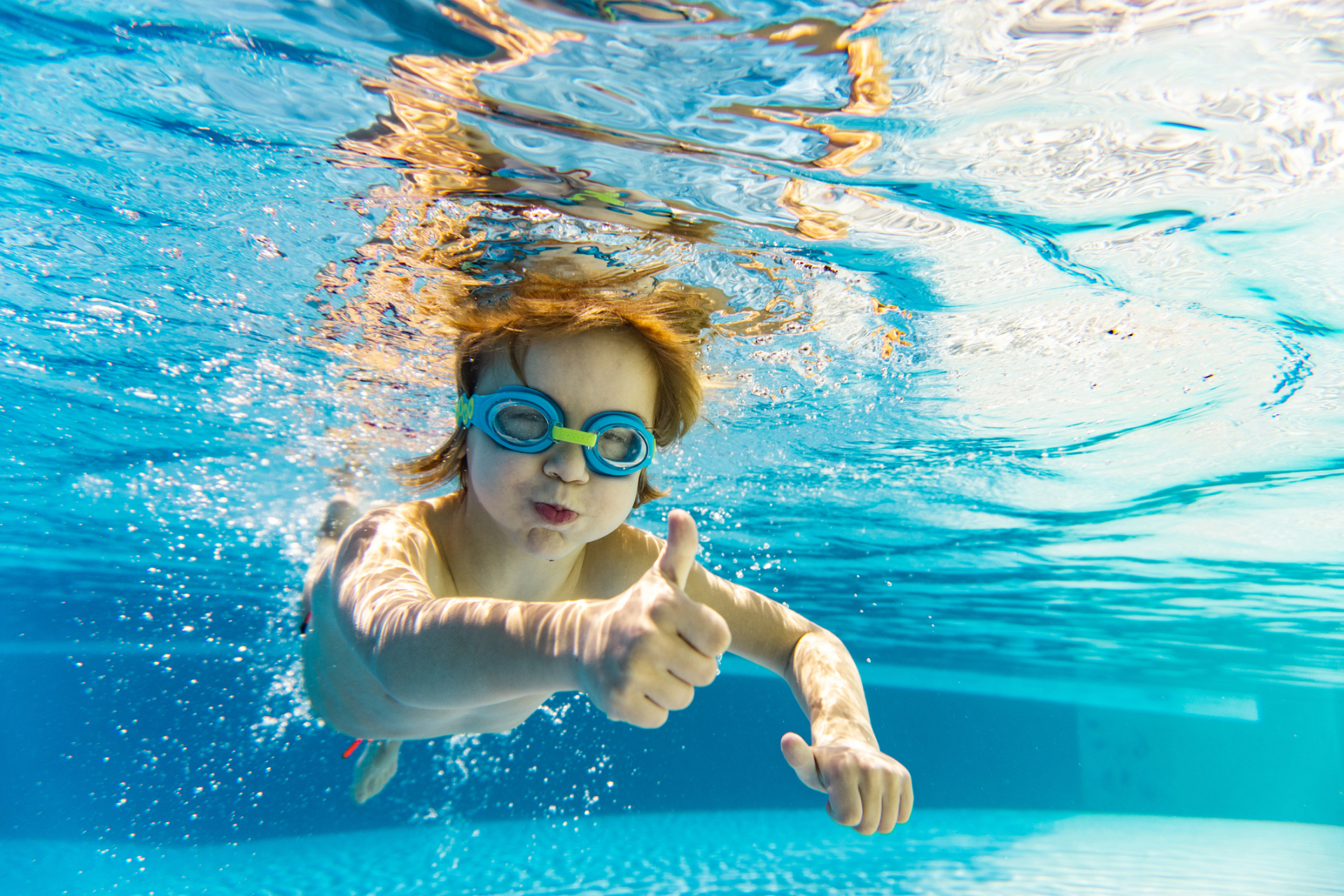 Happy little boy showing thumb up underwater