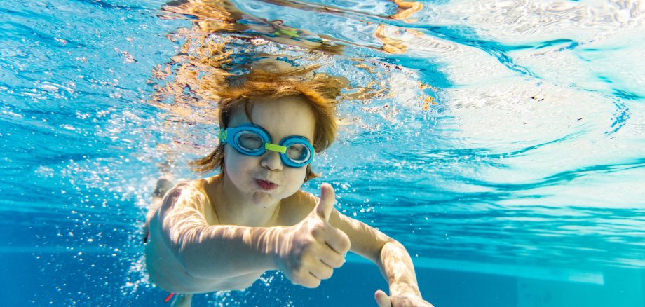 Happy little boy showing thumb up underwater