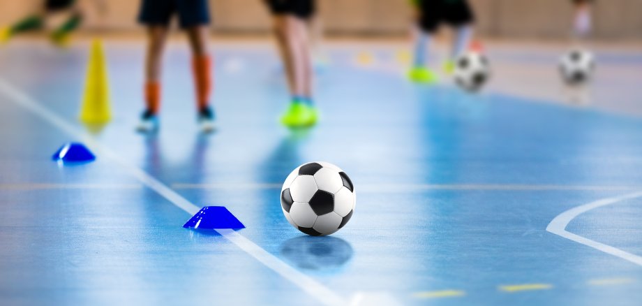 Futsal soccer training field. Young sports players with balls on training. Close up of futsal ball. Futsal Junior Player on Indoor Training. Soccer Winter Class at School Indoor Futsal Court Futsal soccer training field. Young sports players with balls on training. Close up of futsal ball. Futsal Junior Player on Indoor Training. Soccer Winter Class at School Indoor Futsal Court