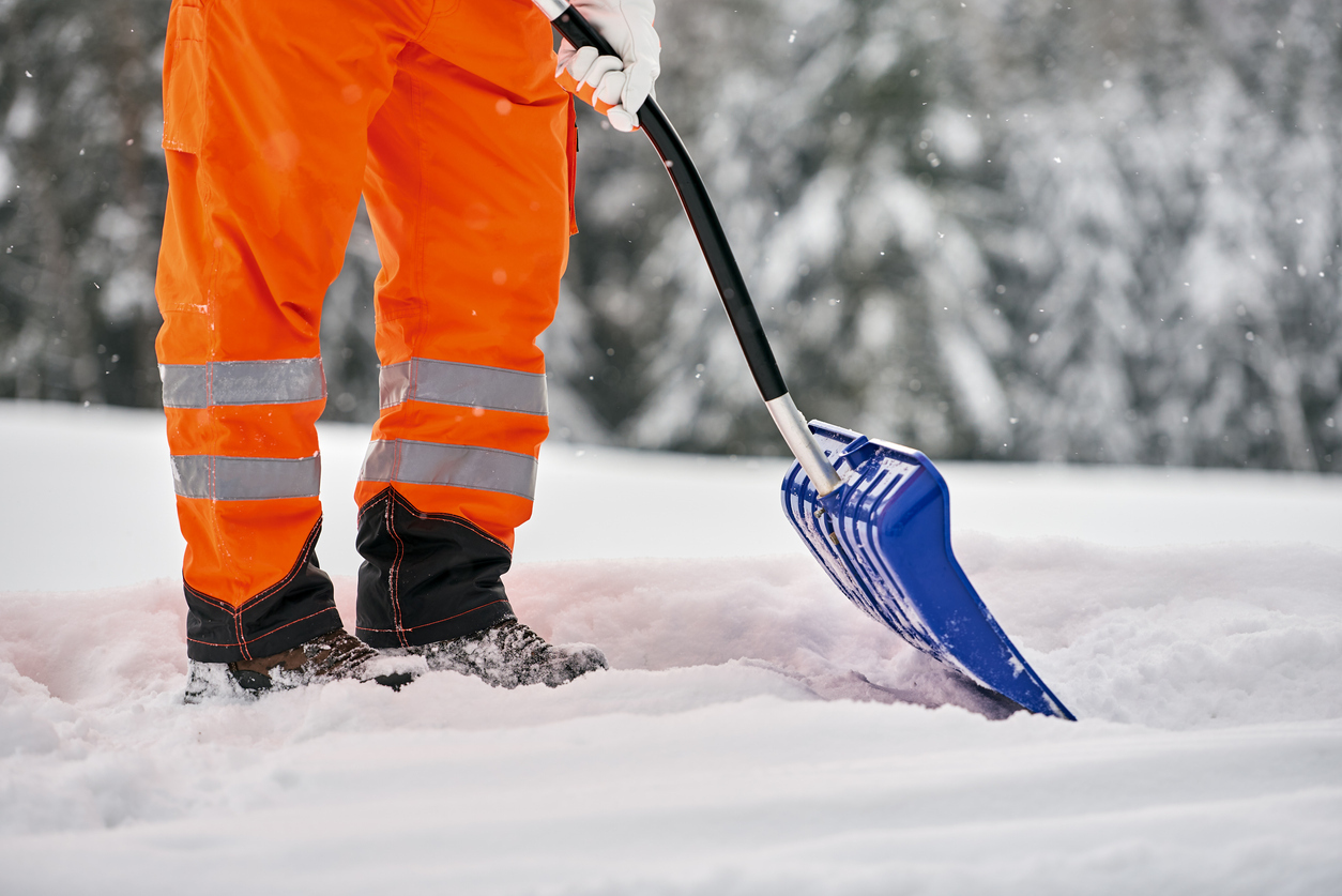 Snow removal, worker sweeps snow from road after winter storm
